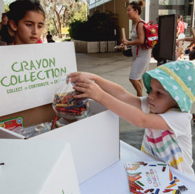A small child donates crayons at Crayon Collection LACMA event
